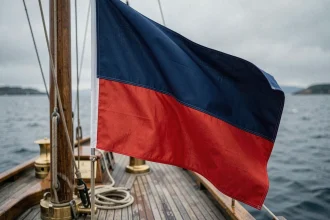 Drapeau bleu et rouge flottant sur un voilier en bois au bord de la mer